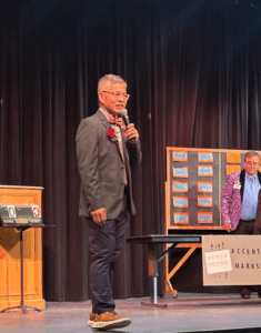 Ben Chan holding microphone and speaking to audience while on stage