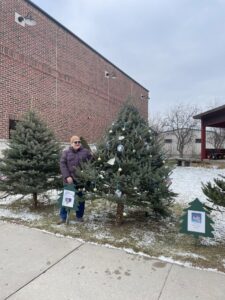 Peggy Wilcox in front of the FMPL memory tree on Depot Street. 2025 The tree was decorated in memory of Robert Redford who passed this year.