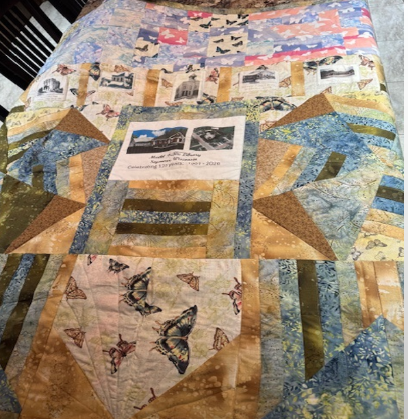 Quilt with images of Seymour libraries through the decades woven in it.